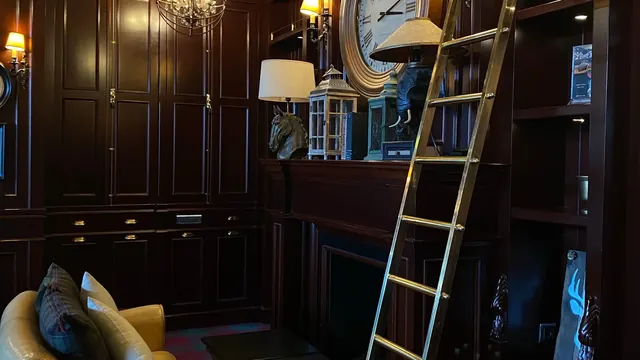 Floor-to-ceiling custom library shelving with a rolling ladder in a Lexington KY home